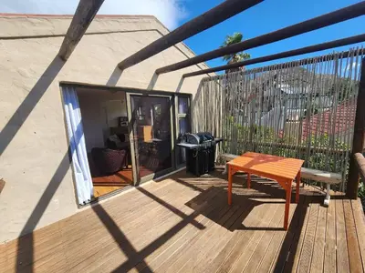 a wooden deck with a bench and a grill at The Sandpiper - The Alikreukel , Pringle Bay in Pringle Bay