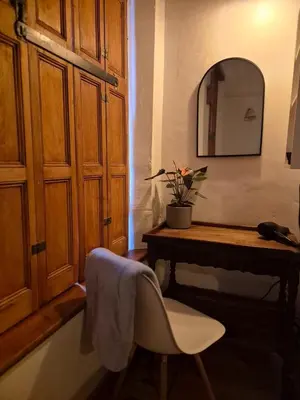 a bathroom with a table and a chair and a mirror at Under the Maple in Rawsonville