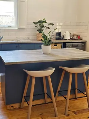 a kitchen with a blue island with two bar stools at Under the Maple in Rawsonville