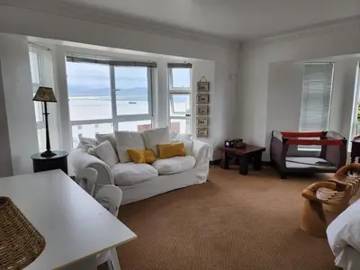 a living room with a white couch and a view of the ocean at Zoute Zoene in Kleinmond