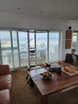 a living room with a wooden table with a view of the ocean at Zoute Zoene in Kleinmond
