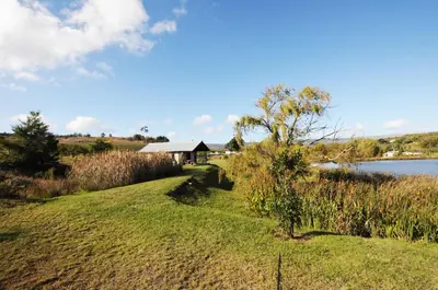 a house on a hill next to a body of water at Galileo Farm in Elgin