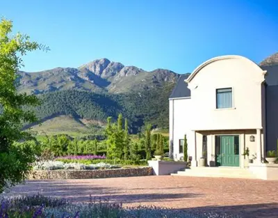 a white building with mountains in the background at Château Famille in Franschhoek