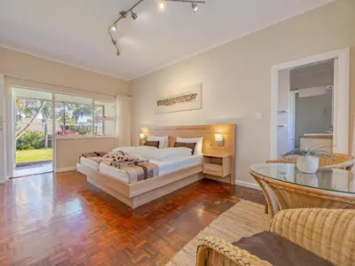 a large bedroom with a bed and a table at Hajo's Lodge & Spa in Cape Town