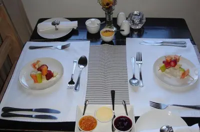a table with plates of food and forks and spoons at Baleia Guest Lodge in Hermanus