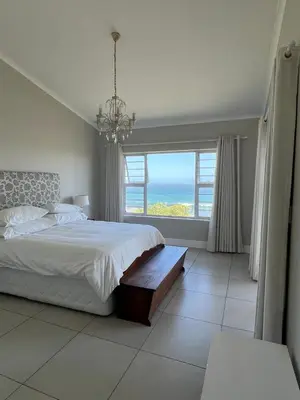 a bedroom with a bed with a view of the ocean at Vermont Hermanus Flatlet in Hermanus