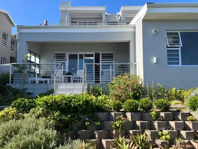 a white house with a porch and some plants at Vermont Hermanus Flatlet in Hermanus