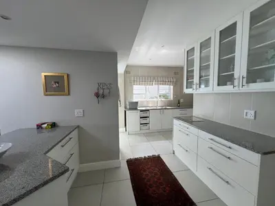 a white kitchen with white cabinets and a sink at Vermont Hermanus Flatlet in Hermanus