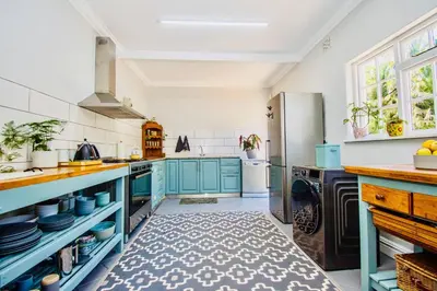 a kitchen with blue cabinets and a refrigerator at Sunny Poolside Escape in Somerset West in Somerset West