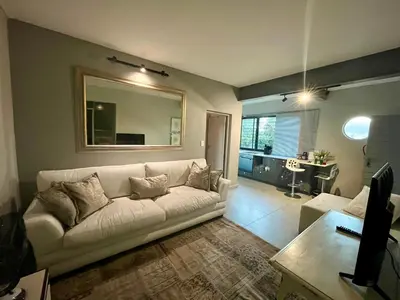 a living room with a white couch and a mirror at Stay on Main 2 in Paarl