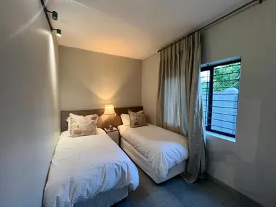 two beds in a room with a window at Stay on Main 2 in Paarl