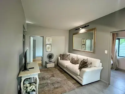 a living room with a white couch and a mirror at Stay on Main 2 in Paarl