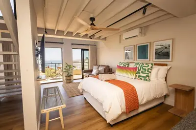 a bedroom with a large bed and a couch at Oceanfront Duplex Apartments, Hermanus Waterfront in Hermanus