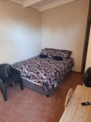 a small bedroom with a bed and a chair at MDA Myburgh in Brackenfell