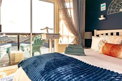 a bedroom with a bed with a view of a balcony at Upper Dunes Apartment in Pringle Bay