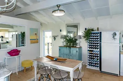 a room with a table with chairs and a refrigerator at Upper Dunes Apartment in Pringle Bay