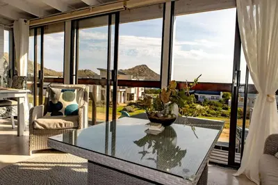 a living room with a glass table and a large window at Upper Dunes Apartment in Pringle Bay