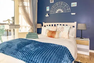 a bedroom with a bed with a blue wall at Upper Dunes Apartment in Pringle Bay