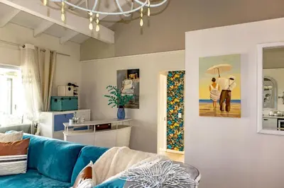 a living room with a blue couch and a painting at Upper Dunes Apartment in Pringle Bay