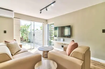 a living room with a couch and a table at Silverview Modern Duplex Fully Air-Conditioned near Beach in Cape Town