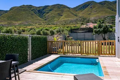 a swimming pool with a fence and mountains in the background at Onrus Family Retreat in Hermanus