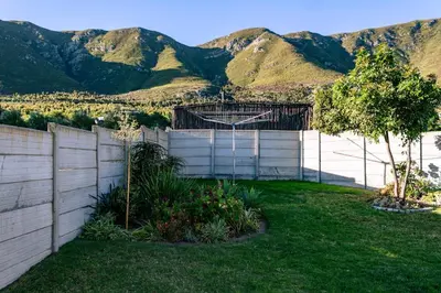 a backyard with a fence and mountains in the background at Onrus Family Retreat in Hermanus
