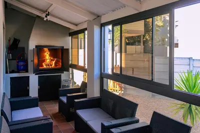 a screened porch with chairs and a fireplace at Onrus Family Retreat in Hermanus