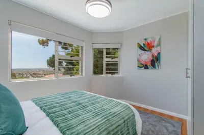 a bedroom with a bed and two windows at 75 on Chapman in Gordonʼs Bay