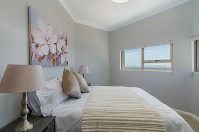 a white bedroom with a bed and a window at 75 on Chapman in Gordonʼs Bay
