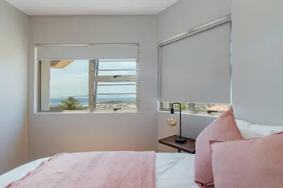 a bedroom with a window with a view of the ocean at 75 on Chapman in Gordonʼs Bay