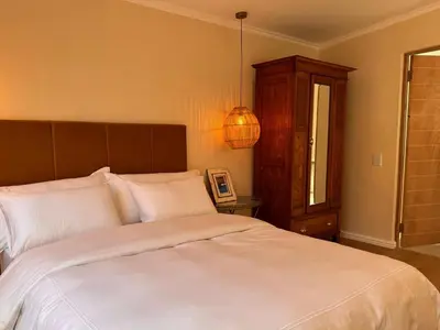 a bedroom with a large bed with white sheets at Mimosa Cottage in Cape Town