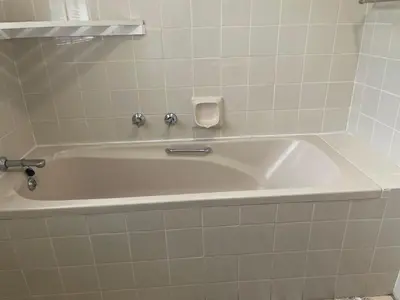 a white bath tub in a bathroom with white tiles at The Garden House in Hermanus