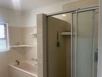 a bathroom with a shower and a bath tub at The Garden House in Hermanus