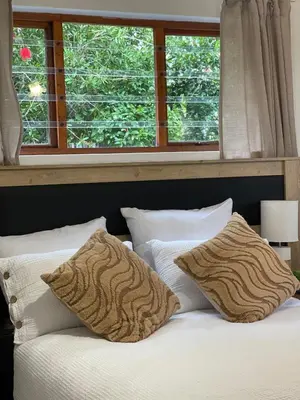 a bed with two pillows sitting under a window at The Garden House in Hermanus