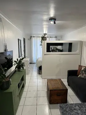a living room with a couch and a tv at A Stone's Throw away in Cape Town