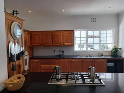 a kitchen with wooden cabinets and a stove top oven at Spacious Family Home - Windsor Retreats in Somerset West