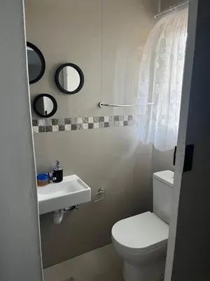 a bathroom with a white toilet and a sink at SNE Travellers in Faure