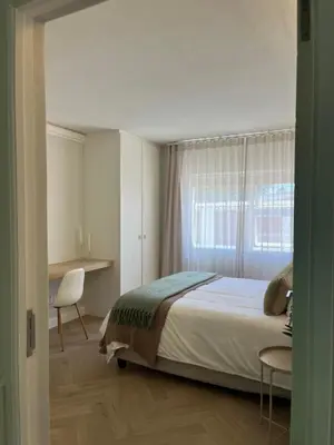 a bedroom with a bed and a desk and a window at Nomads Hermanus in Hermanus