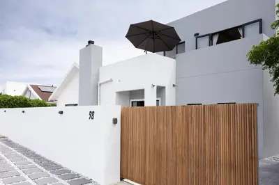 a white house with a wooden fence and an umbrella at 5 Bedroom Family Home with Private Apartment in Hermanus