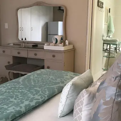 a bedroom with a bed and a sink and a mirror at Bay Breeze Guesthouse Selfcatering in Gordonʼs Bay