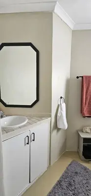 a bathroom with a sink and a mirror and a rug at Kite Surfers Haven in Cape Town