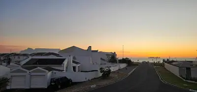 a street with houses and a sunset in the background at Kite Surfers Haven in Cape Town