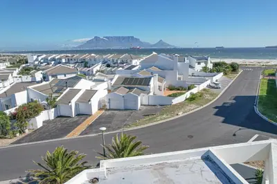 a row of houses on a street next to the ocean at Kite Surfers Haven in Cape Town