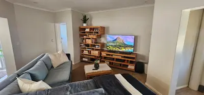 a living room with a couch and a flat screen tv at Kite Surfers Haven in Cape Town