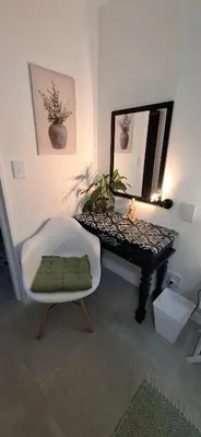 a room with a mirror and a chair and a piano at Grey Vine Cottage - Flatlet in Cape Town