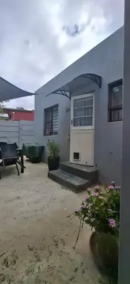 a white house with a door and a patio at Grey Vine Cottage - Flatlet in Cape Town
