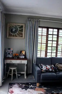 a living room with a couch and a desk at Fijnbos - Something-Els in Rooiels