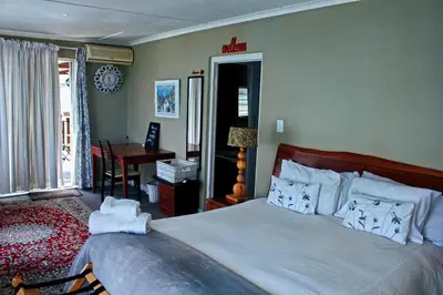 a bedroom with a bed and a table and a desk at Fijnbos - Something-Els in Rooiels