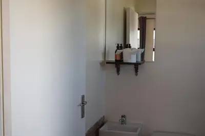 a white bathroom with a sink and a mirror at The Crest Studio in Oakdale