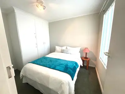 a bedroom with a white bed with a blue blanket at 111 Hermanus beach club in Hermanus